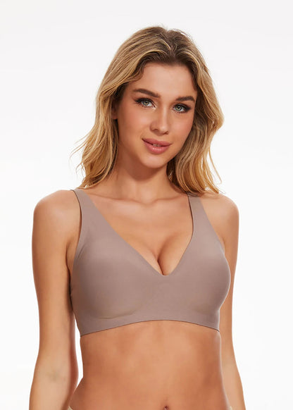 Woman wearing a beige bralette against a plain background